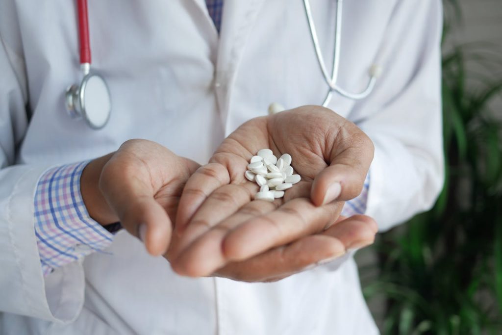 person-holding-white-pills-8763983 A close-up of a doctor holding white pills in their palms, emphasizing healthcare and medicine.